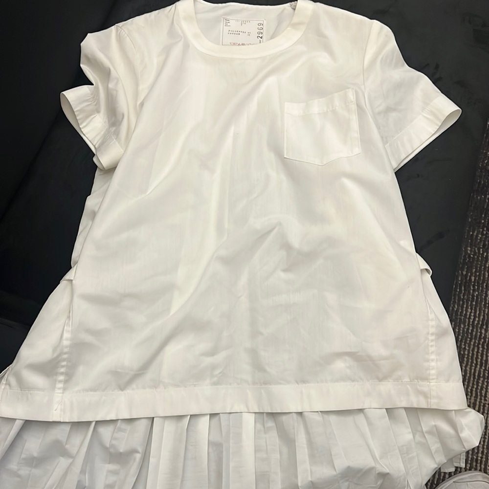 White Sacai blouse with zipper on shoulder, high collar short sleeve.